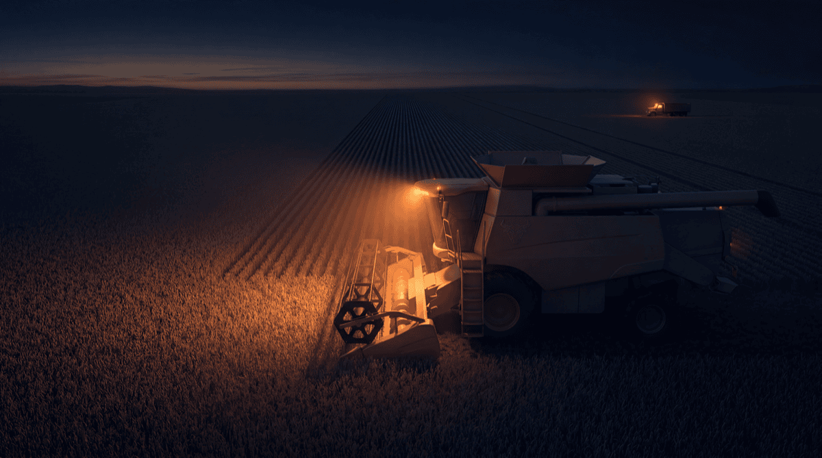 A combine harvester working a vast field at night with its header lit in warm orange and long harvested rows behind it, while a single farmer's truck waits at the field edge, representing machines doing the high-volume work under human oversight